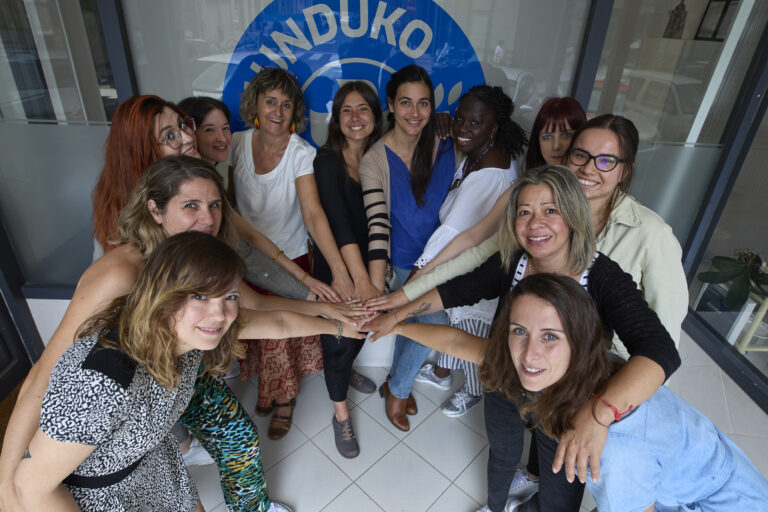 Fotografía del equipo de la sede autonómica de Médicos del Mundo Navarra en la entrada a la oficina de Pamplona uniendo sus manos.